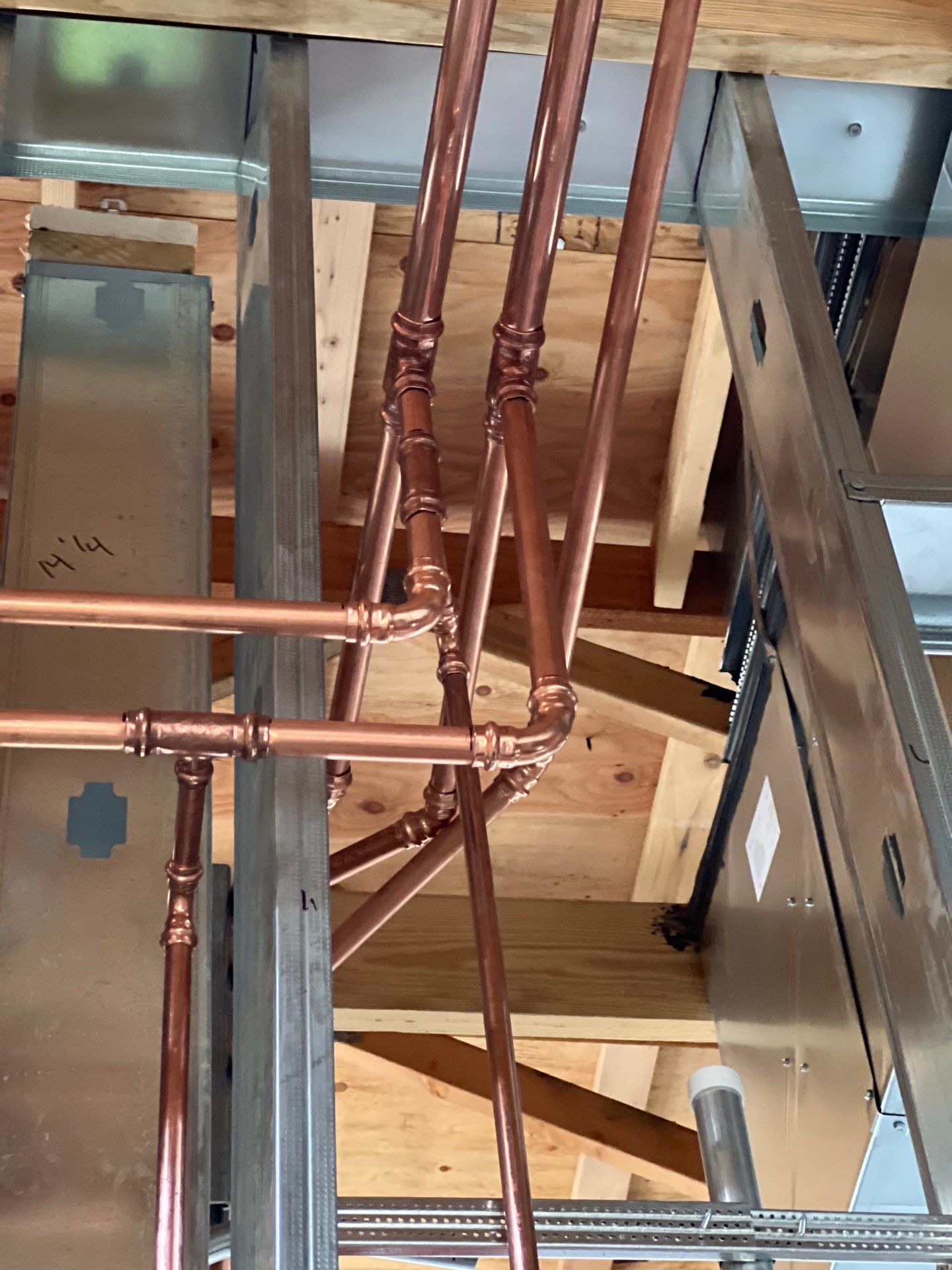 Neatly organized copper pipe runs through steel framing demonstrating craftsmanship
